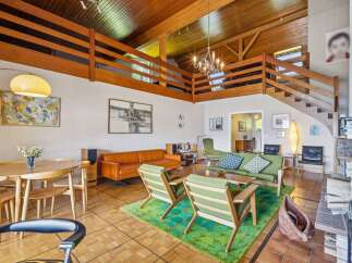Experience mid-century modern living in this stunning home featuring a dramatic vaulted wood-beamed ceiling and an open loft space.