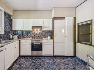This charming kitchen features a unique blue and brown tiled backsplash and matching floor, creating a retro yet stylish aesthetic.