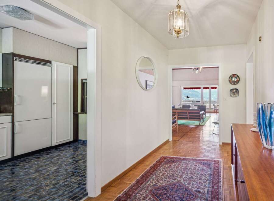 Step into this charming hallway featuring a vintage rug and a decorative mirror, leading to a bright living area with stunning mountain views.