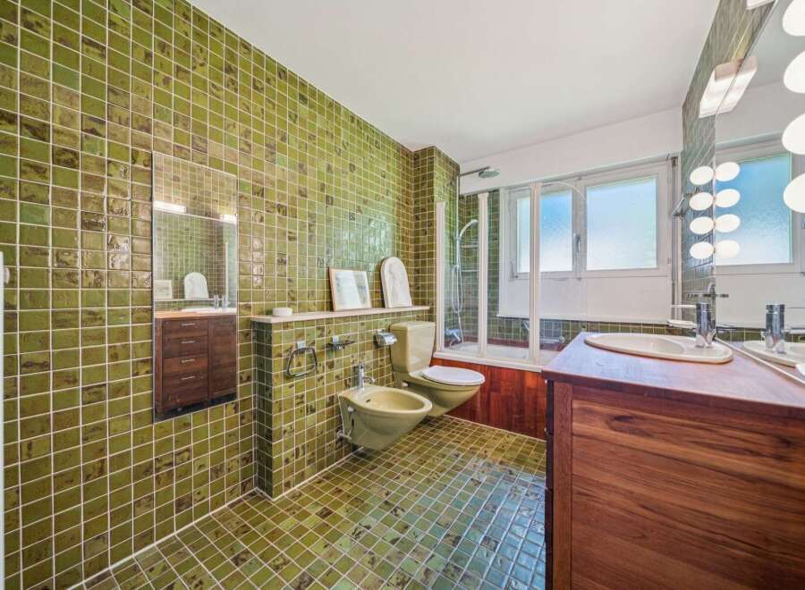 Step into this uniquely designed bathroom featuring vibrant green tiled walls and floors, creating a retro yet refreshing ambiance.