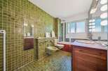Step into this uniquely designed bathroom featuring vibrant green tiled walls and floors, creating a retro yet refreshing ambiance.