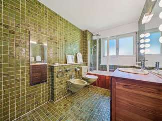 Step into this uniquely designed bathroom featuring vibrant green tiled walls and floors, creating a retro yet refreshing ambiance.