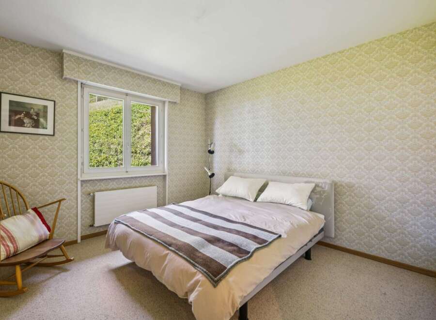 This charming bedroom features a comfortable bed adorned with a striped throw and plush pillows, perfect for a restful night's sleep.