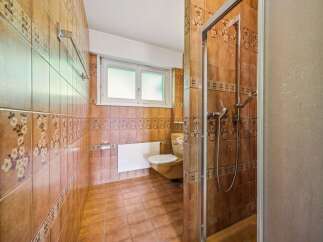 This bathroom features warm, earthy tones with decorative floral tiles and a complementary tiled floor.