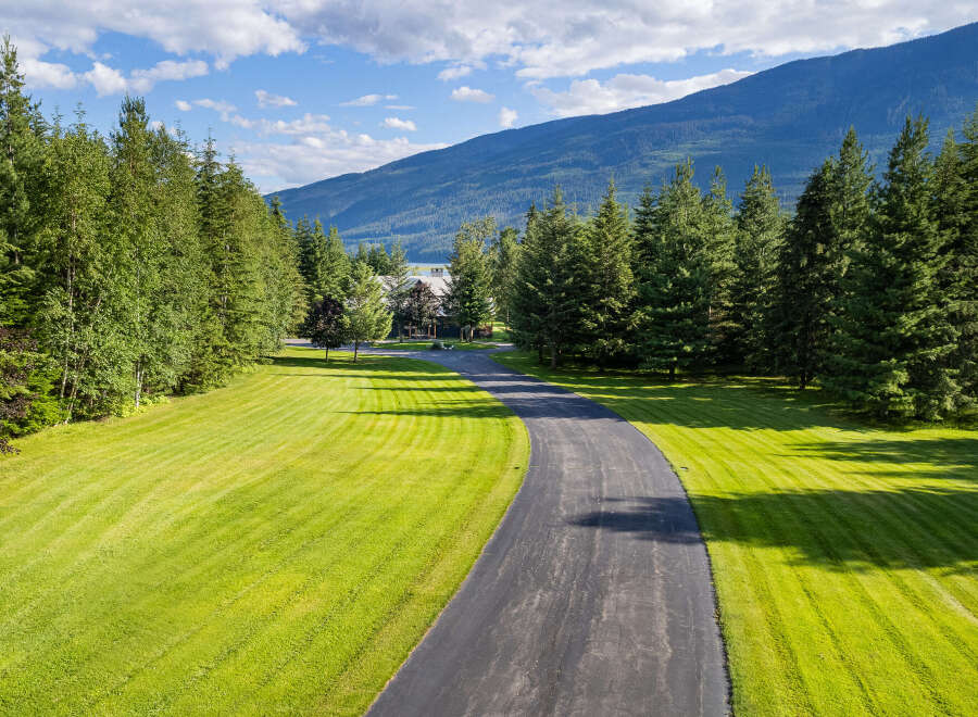 Discover this stunning property featuring a winding asphalt driveway leading to a beautiful home nestled amongst mature trees.