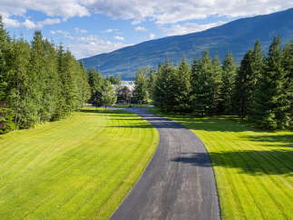 Discover this stunning property featuring a winding asphalt driveway leading to a beautiful home nestled amongst mature trees.