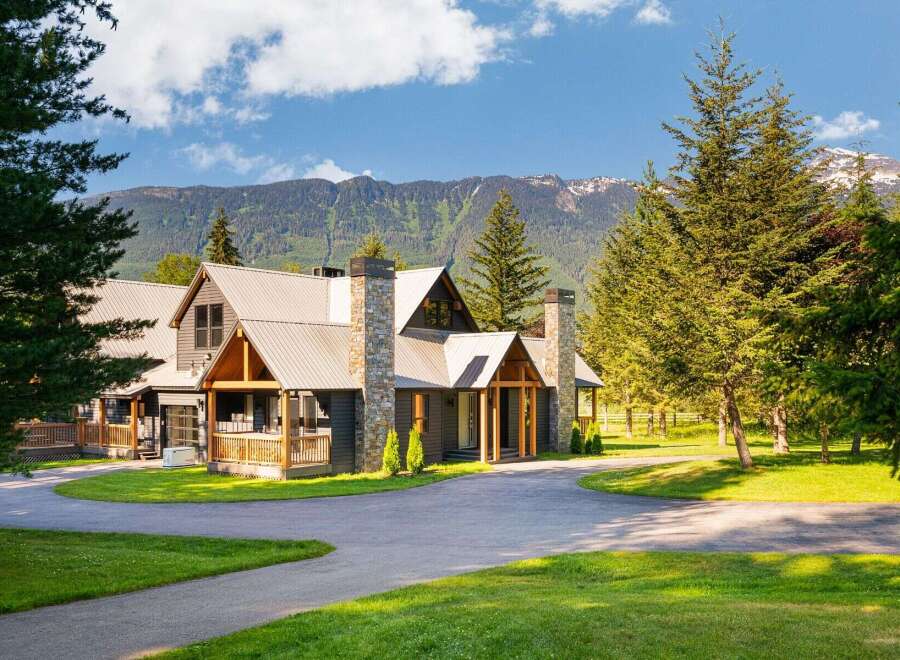 Experience luxury mountain living in this stunning lodge-style home, featuring a durable metal roof and striking stone chimneys.