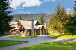 Experience luxury mountain living in this stunning lodge-style home, featuring a durable metal roof and striking stone chimneys.