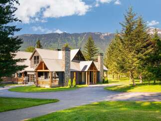 Experience luxury mountain living in this stunning lodge-style home, featuring a durable metal roof and striking stone chimneys.