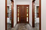 Step into a grand entryway featuring a rich, dark wood door with elegant glass panels, inviting natural light into the home.