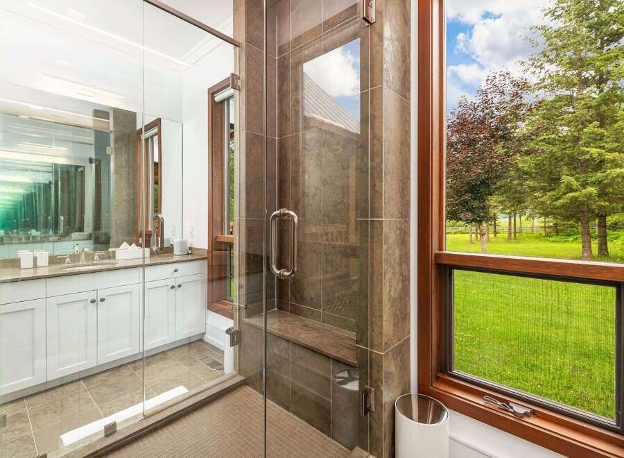 Experience luxury in this stunning bathroom featuring a spacious glass-enclosed shower with a built-in bench and elegant tilework.