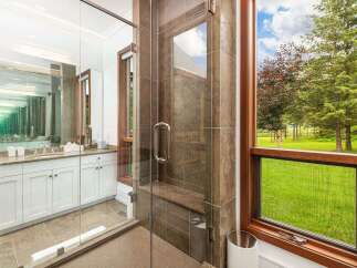 Experience luxury in this stunning bathroom featuring a spacious glass-enclosed shower with a built-in bench and elegant tilework.