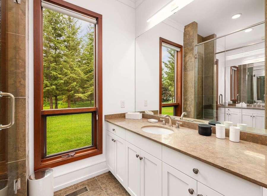Experience luxury and nature combined in this stunning bathroom, featuring a spacious vanity with a granite countertop and ample storage.
