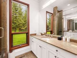 Experience luxury and nature combined in this stunning bathroom, featuring a spacious vanity with a granite countertop and ample storage.
