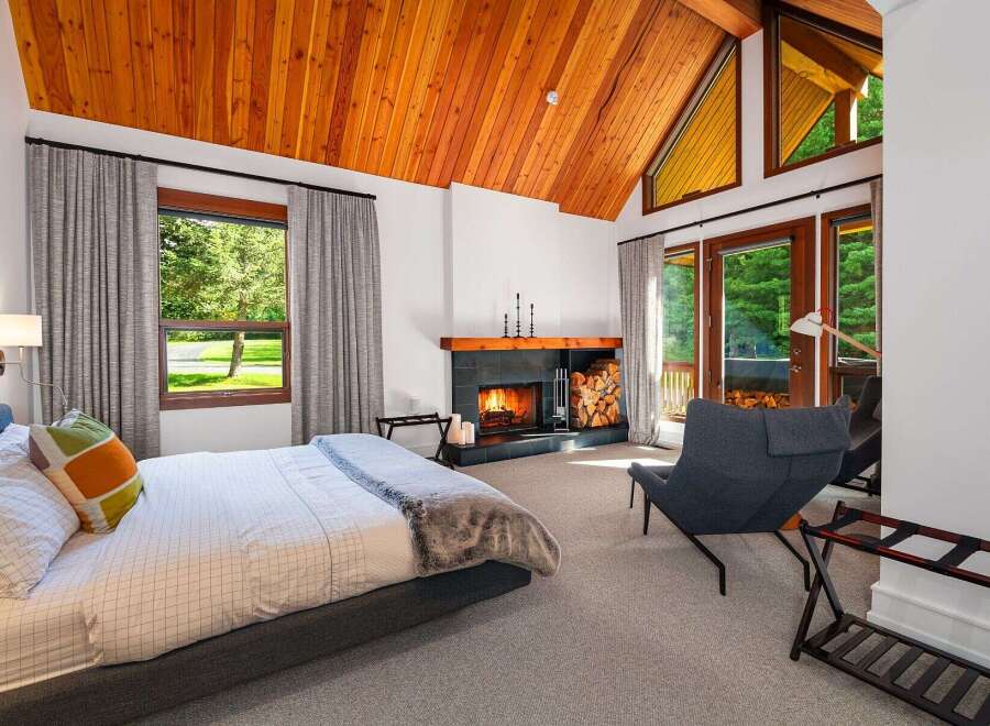 Experience ultimate relaxation in this luxurious bedroom featuring a cozy fireplace and stunning vaulted wood-paneled ceilings.