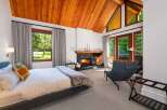 Experience ultimate relaxation in this luxurious bedroom featuring a cozy fireplace and stunning vaulted wood-paneled ceilings.
