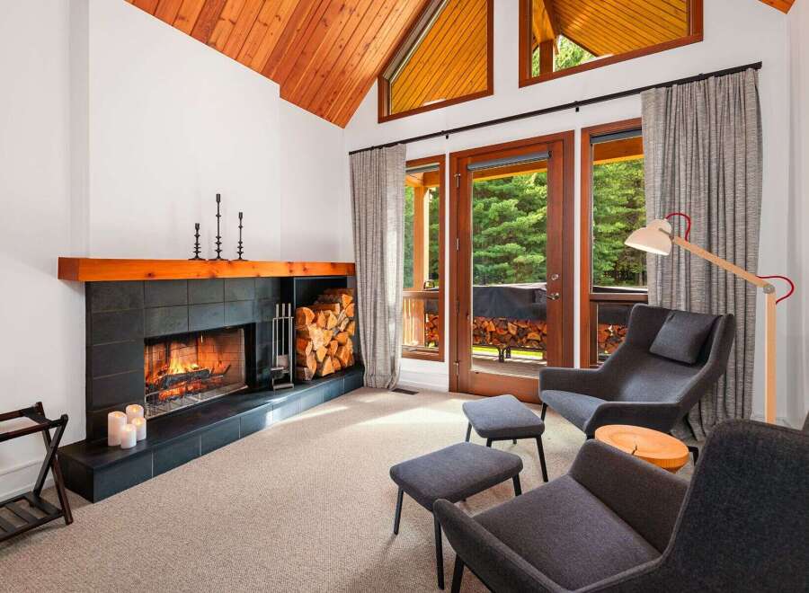 Experience cozy living in this inviting room featuring a striking fireplace with a wooden mantel and ample firewood storage.