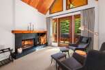 Experience cozy living in this inviting room featuring a striking fireplace with a wooden mantel and ample firewood storage.
