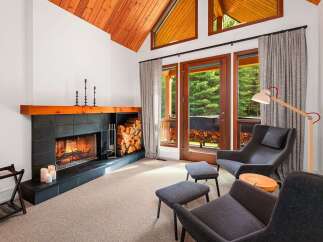 Experience cozy living in this inviting room featuring a striking fireplace with a wooden mantel and ample firewood storage.
