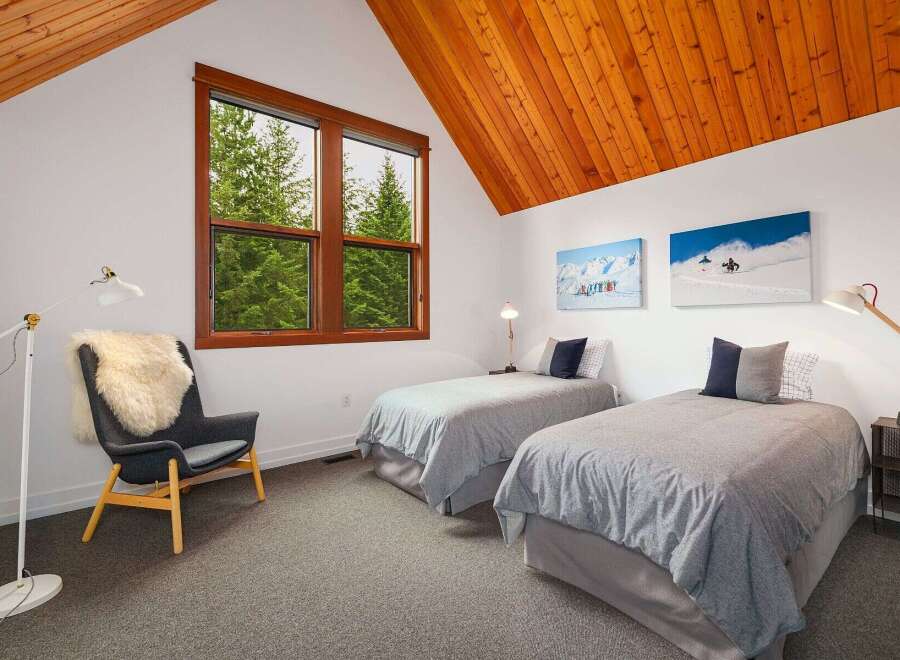 This charming bedroom features two twin beds with cozy grey bedding, perfect for guests or family.