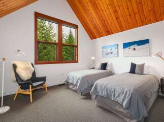This charming bedroom features two twin beds with cozy grey bedding, perfect for guests or family.
