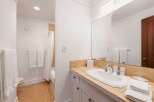 This bright and clean bathroom features a spacious vanity with a tiled countertop and a large mirror, perfect for morning routines.