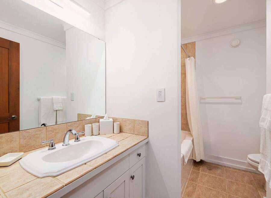 This bathroom features a clean white sink with chrome fixtures set against a tiled backsplash.