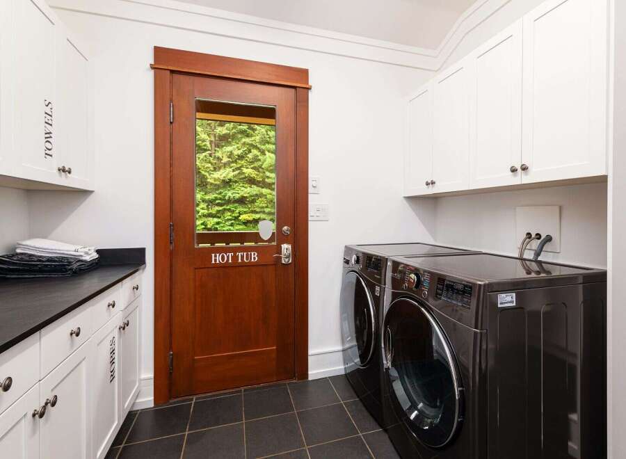 This laundry room offers ample storage with white cabinetry, including a cabinet labeled 'TOWELS' and another labeled 'ROBES'.