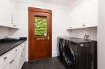 This laundry room offers ample storage with white cabinetry, including a cabinet labeled 'TOWELS' and another labeled 'ROBES'.