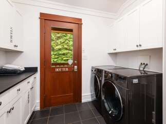 This laundry room offers ample storage with white cabinetry, including a cabinet labeled 'TOWELS' and another labeled 'ROBES'.