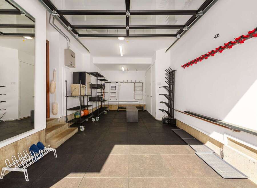 This spacious garage offers ample storage solutions, including multi-tiered shelving units and wall-mounted racks perfect for skis and sports equipment.