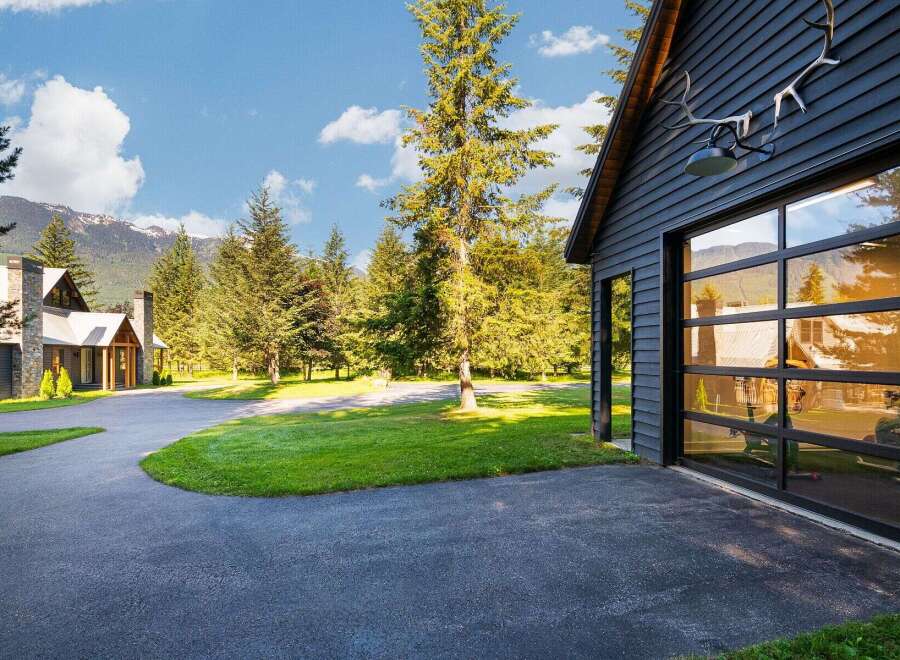 Experience luxury mountain living in this stunning property, featuring a modern dark wood exterior and a striking glass garage door.