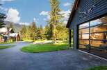 Experience luxury mountain living in this stunning property, featuring a modern dark wood exterior and a striking glass garage door.