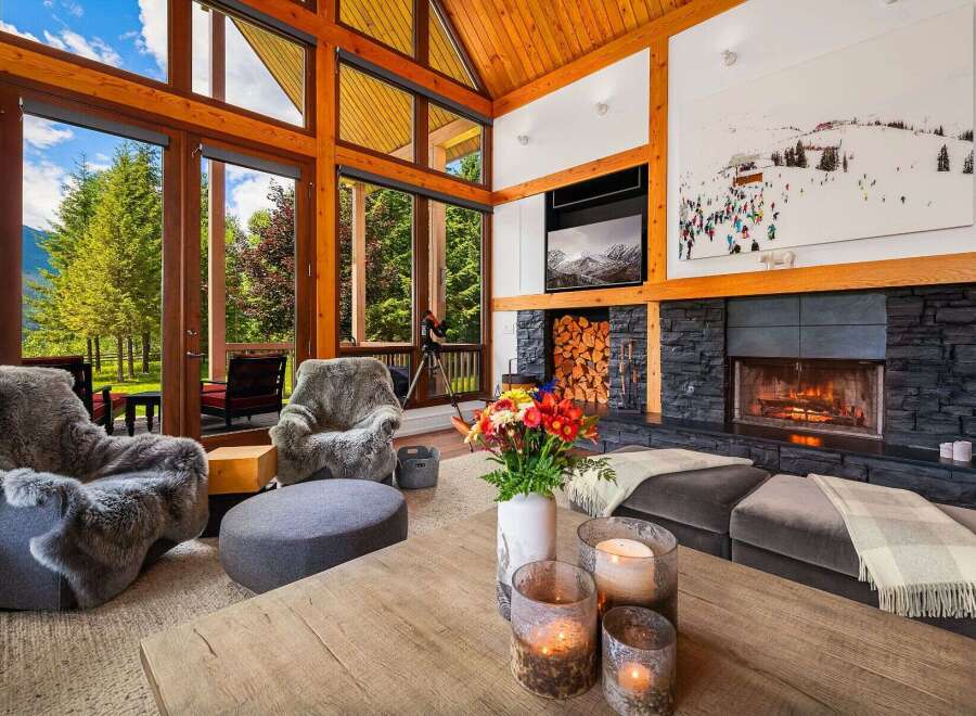 Experience luxury mountain living in this stunning great room, featuring soaring vaulted ceilings with exposed wooden beams and a magnificent stone fireplace.