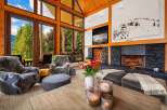 Experience luxury mountain living in this stunning great room, featuring soaring vaulted ceilings with exposed wooden beams and a magnificent stone fireplace.