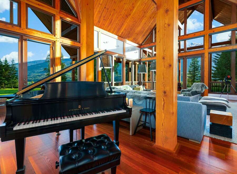 Experience luxury living in this stunning mountain retreat, featuring a grand piano and expansive windows that showcase breathtaking panoramic views.