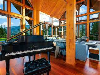 Experience luxury living in this stunning mountain retreat, featuring a grand piano and expansive windows that showcase breathtaking panoramic views.