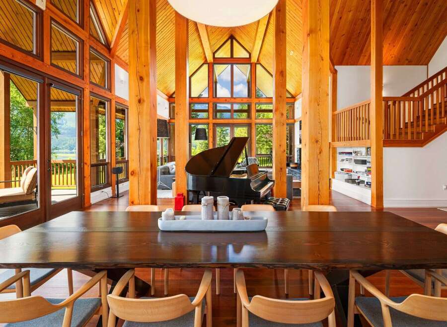 Experience luxury living in this stunning home featuring a grand piano and soaring vaulted ceilings with exposed wooden beams.