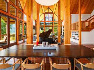 Experience luxury living in this stunning home featuring a grand piano and soaring vaulted ceilings with exposed wooden beams.