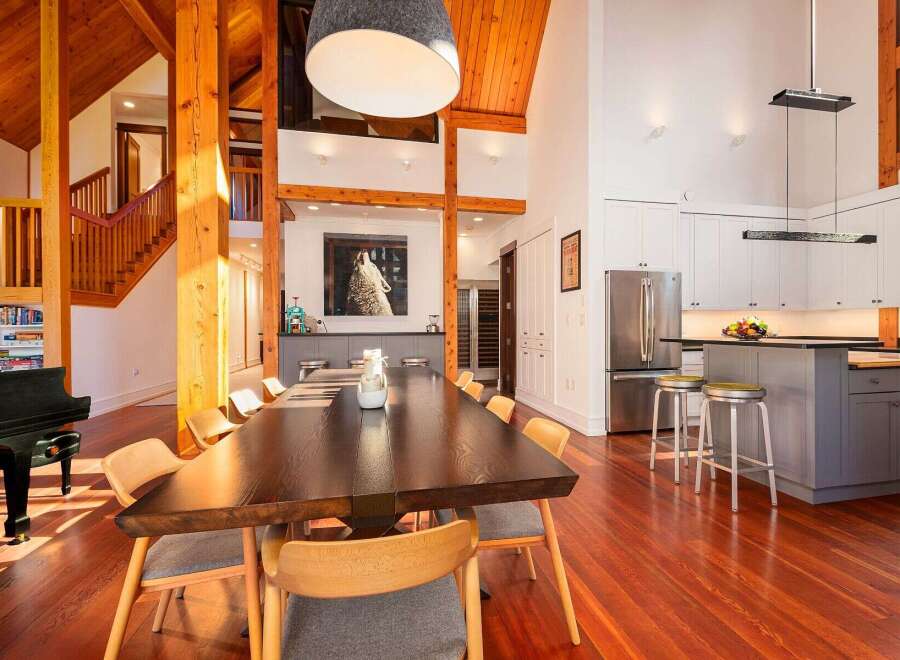 Experience luxurious living in this stunning open-concept home featuring a grand dining area with a large wooden table, perfect for entertaining.