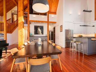 Experience luxurious living in this stunning open-concept home featuring a grand dining area with a large wooden table, perfect for entertaining.