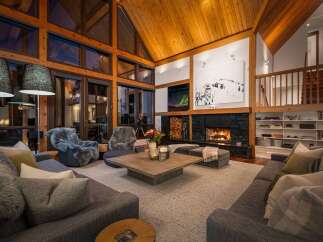 Experience ultimate luxury in this stunning mountain lodge living room, featuring a grand stone fireplace and soaring wooden ceilings.