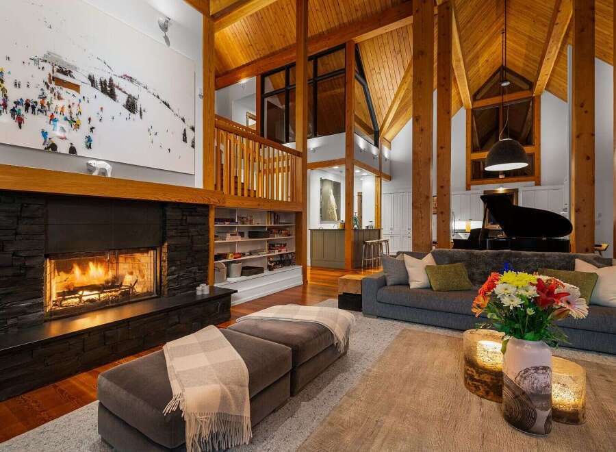 Experience luxury mountain living in this stunning lodge-style home, featuring a grand stone fireplace and soaring vaulted ceilings with exposed wooden beams.