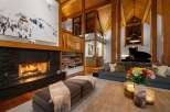Experience luxury mountain living in this stunning lodge-style home, featuring a grand stone fireplace and soaring vaulted ceilings with exposed wooden beams.