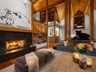 Experience luxury mountain living in this stunning lodge-style home, featuring a grand stone fireplace and soaring vaulted ceilings with exposed wooden beams.