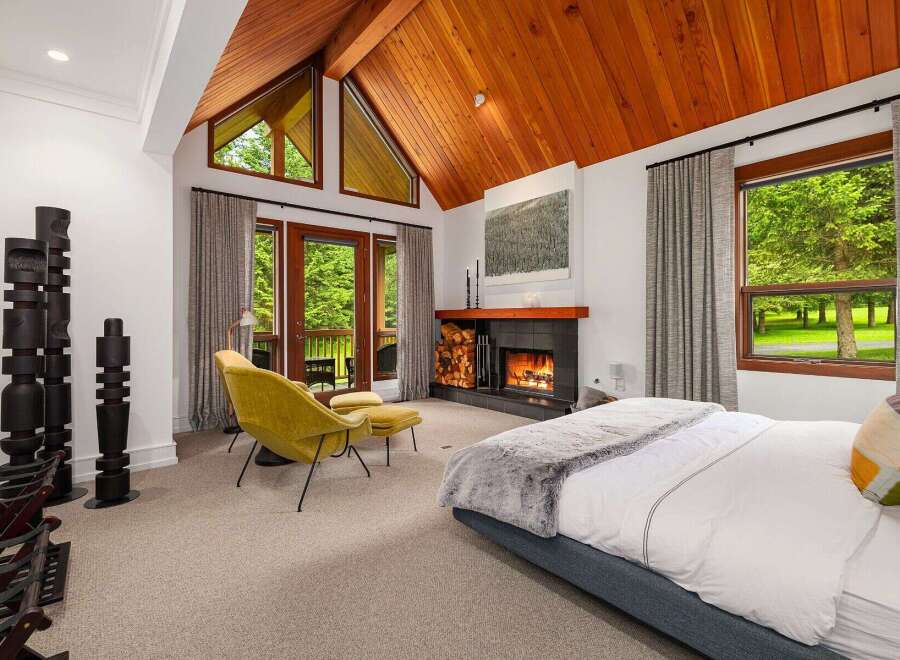 Experience luxury living in this stunning bedroom featuring a cozy fireplace and a comfortable seating area.