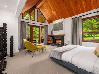 Experience luxury living in this stunning bedroom featuring a cozy fireplace and a comfortable seating area.