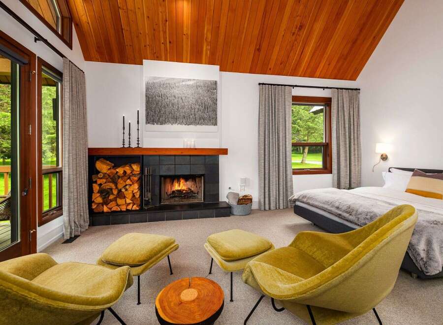 Experience ultimate relaxation in this cozy bedroom featuring a crackling fireplace and comfortable seating area.