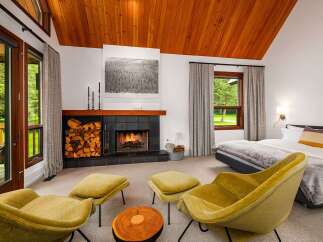 Experience ultimate relaxation in this cozy bedroom featuring a crackling fireplace and comfortable seating area.