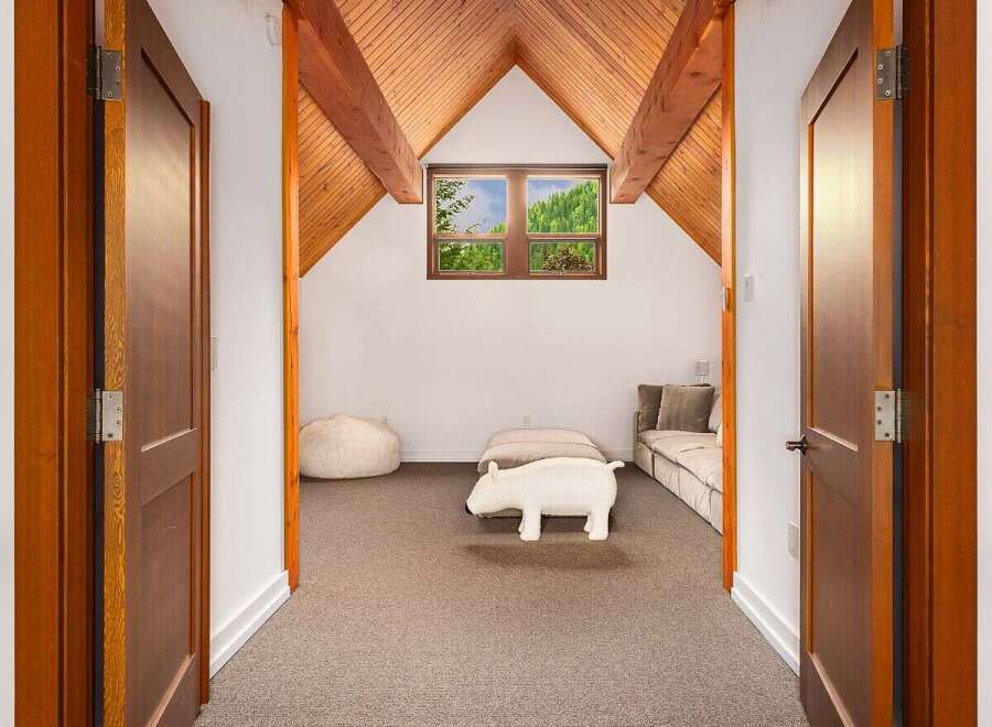 Step into this charming attic room, featuring a vaulted wooden ceiling and a cozy seating area perfect for relaxation.